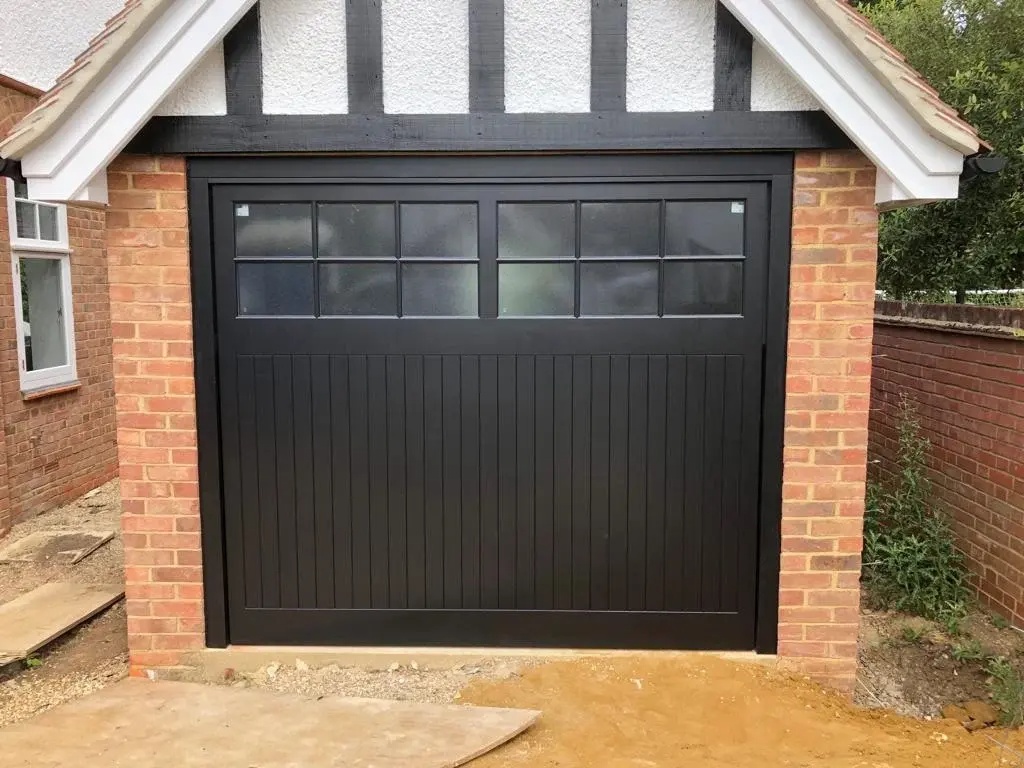 Garage door repair Pasadena — black carriage-style door with glass panels on traditional brick property