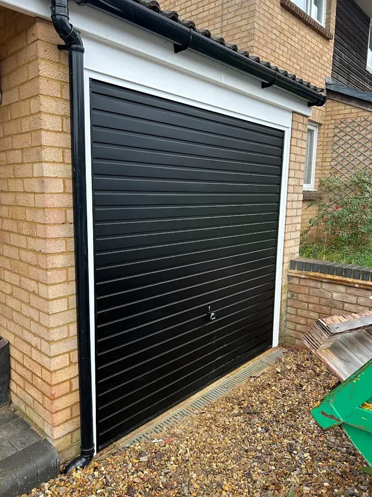 Black roller garage door installed on single garage of brick residential home